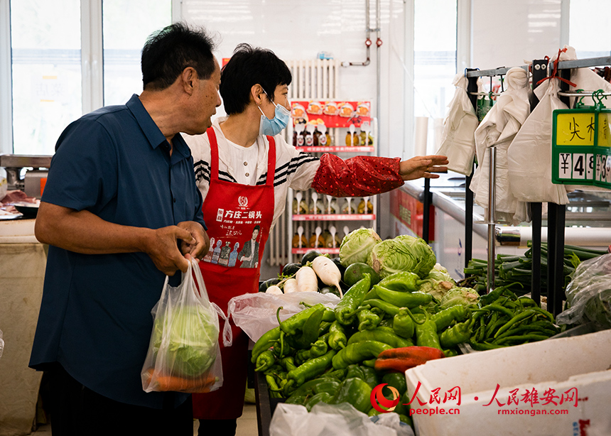 菜店內(nèi)，工作人員正在為顧客提供幫助。出門就是菜店，吃飯不發(fā)愁，成為容東片區(qū)居民的日常。人民網(wǎng)?宋燁文攝